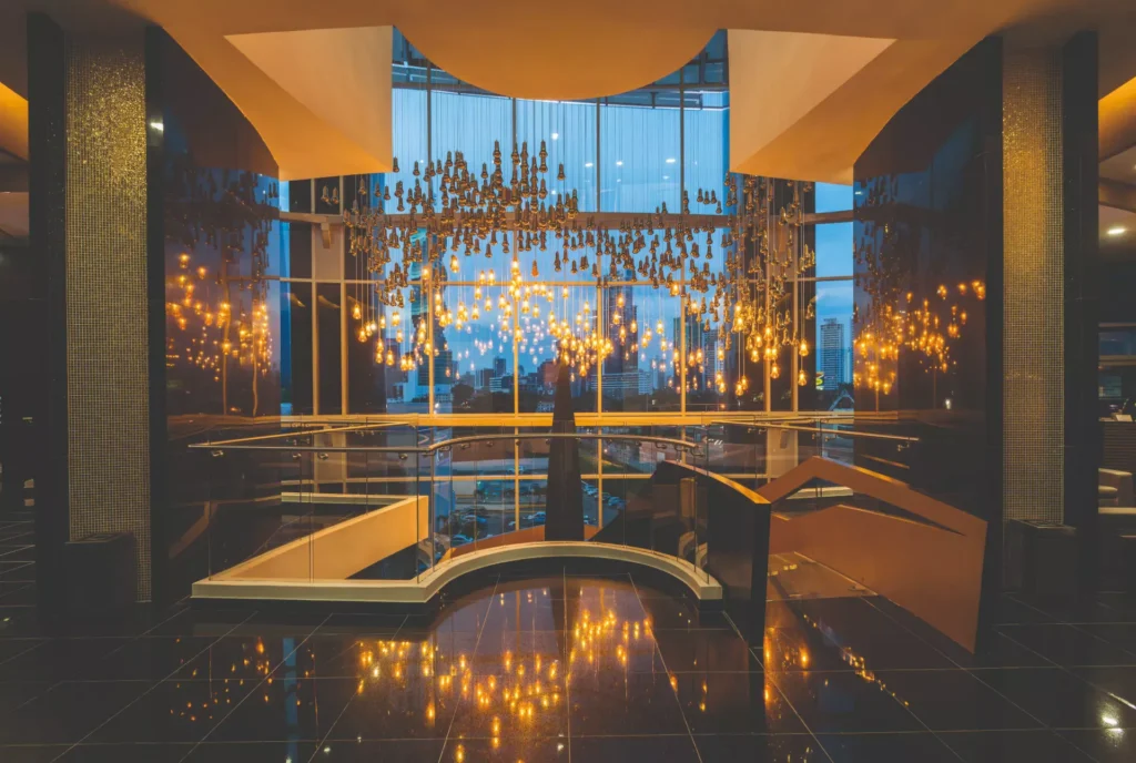 Lujoso vestíbulo de Local Smiles con una gran lámpara colgante y ventanales que muestran la ciudad.